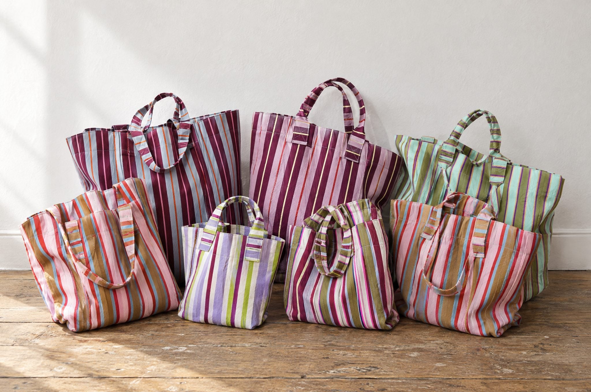 Cassia Essentiels striped totes in every colourway on a wooden table