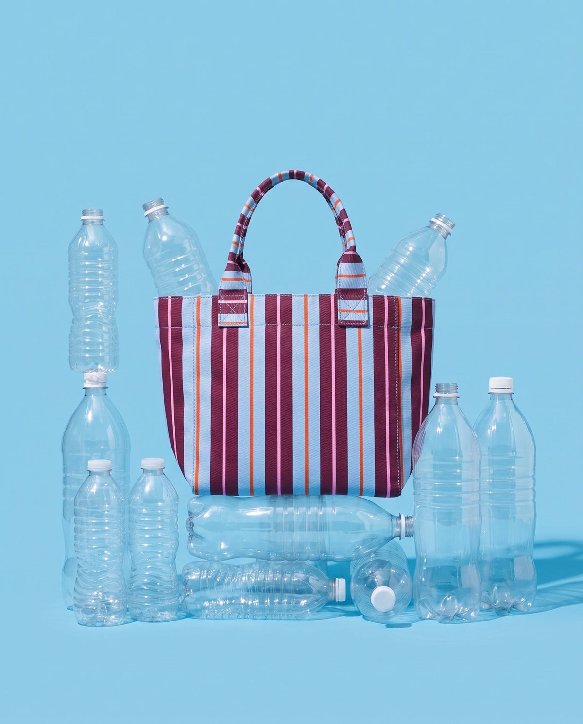 A striped Cassia tote surrounded by clear plastic bottles